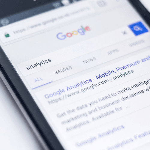 A smartphone screen shows a Google search for analytics, displaying search results and the Google logo.