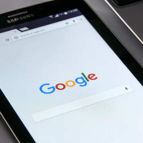A smartphone with the Google search homepage beside a laptop keyboard—perfect for website or digital marketing tasks.