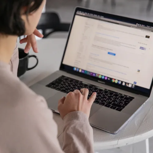 Person using a laptop at a table, viewing a digital marketing dashboard with a coffee mug nearby.